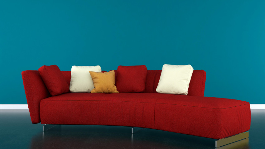 Red sofa with pillows in an empty blue room.