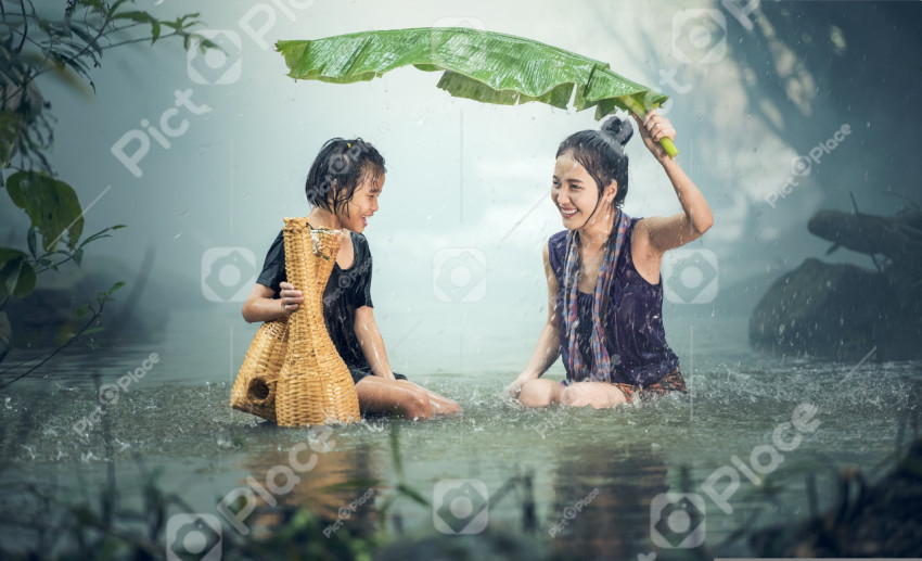 A woman with a child hiding from the rain under a large leaf