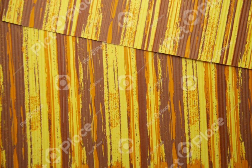 Two sheets of corrugated thick paper lie on top of each other. Sheets are painted in yellow-orange-cinnamon colors