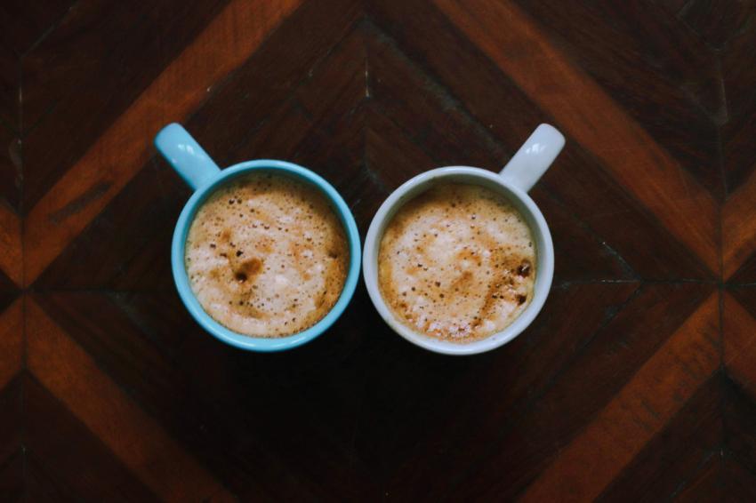 two cups of coffee placed on a wooden table