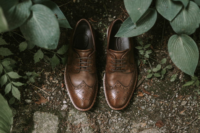 Men's wedding shoes stand on the ground among plants