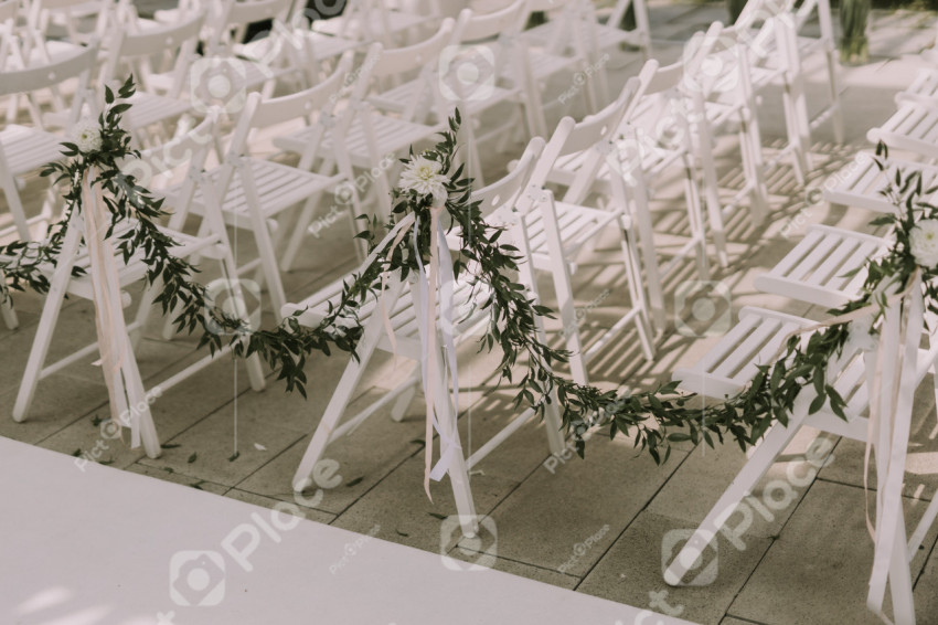 White chairs decorated for a wedding ceremony