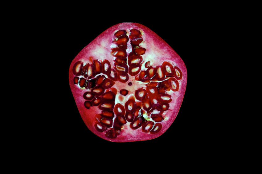 Cut pomegranate fruit on a black background