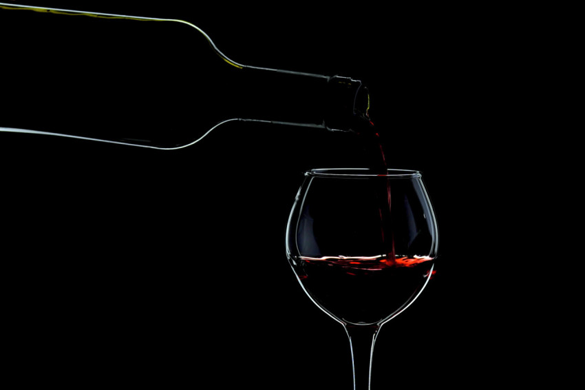 Bottle of wine, wineglass, counter light, black background