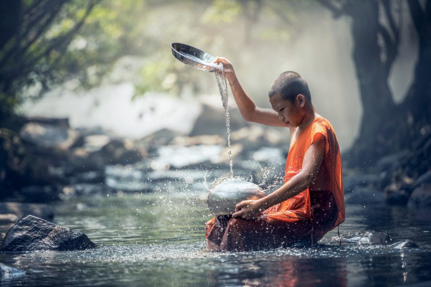 Boy washing dishes by the river