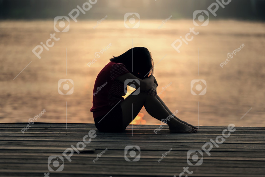 Sad girl at sunset by the water