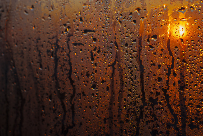 Raindrops on glass against the background of the sun. Autumn abstract background