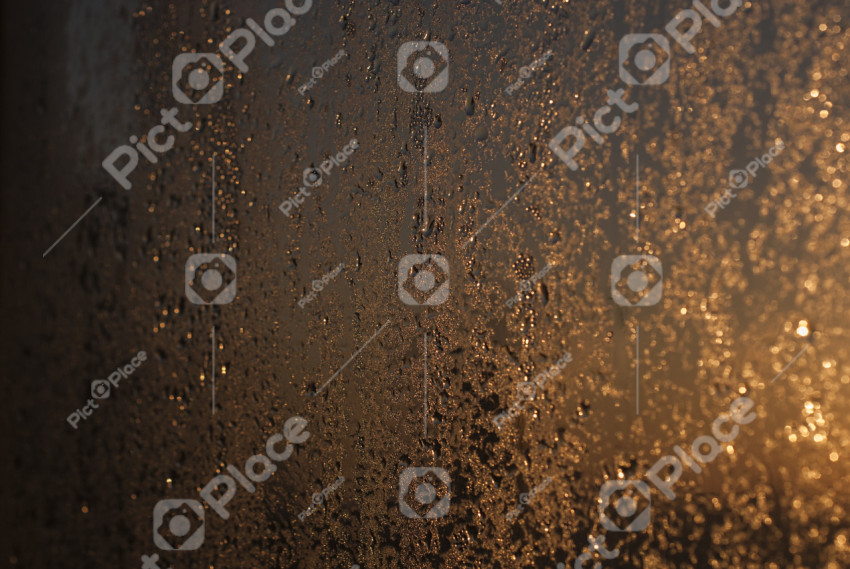 Raindrops on glass against the background of the sun. Abstract background