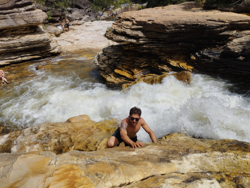 a man in climbs on the rocks against the backdrop of a stormy river