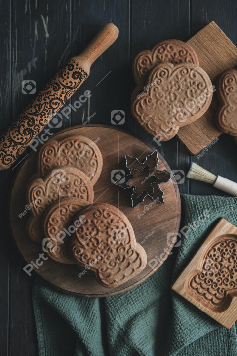 wooden cutting board topped with cookies next to a cookie cutter