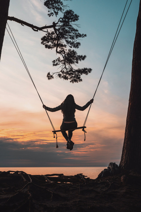 Silhouette of a man sitting on a swing during sunset