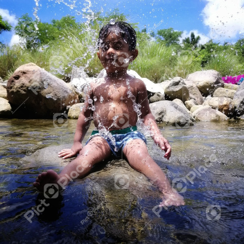 Boy in splashes of water sitting in a stream